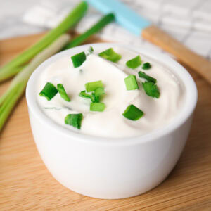 Fresh sour cream with onion on wooden board