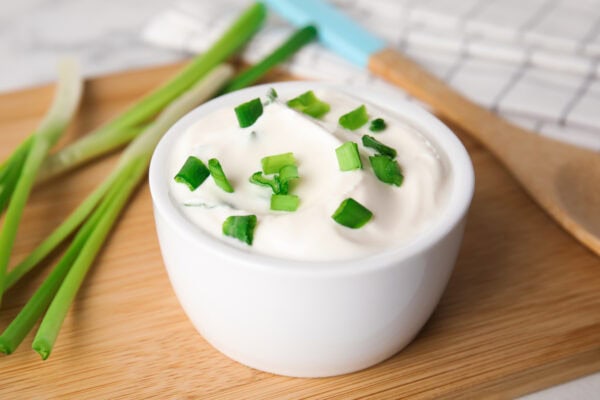 Fresh sour cream with onion on wooden board